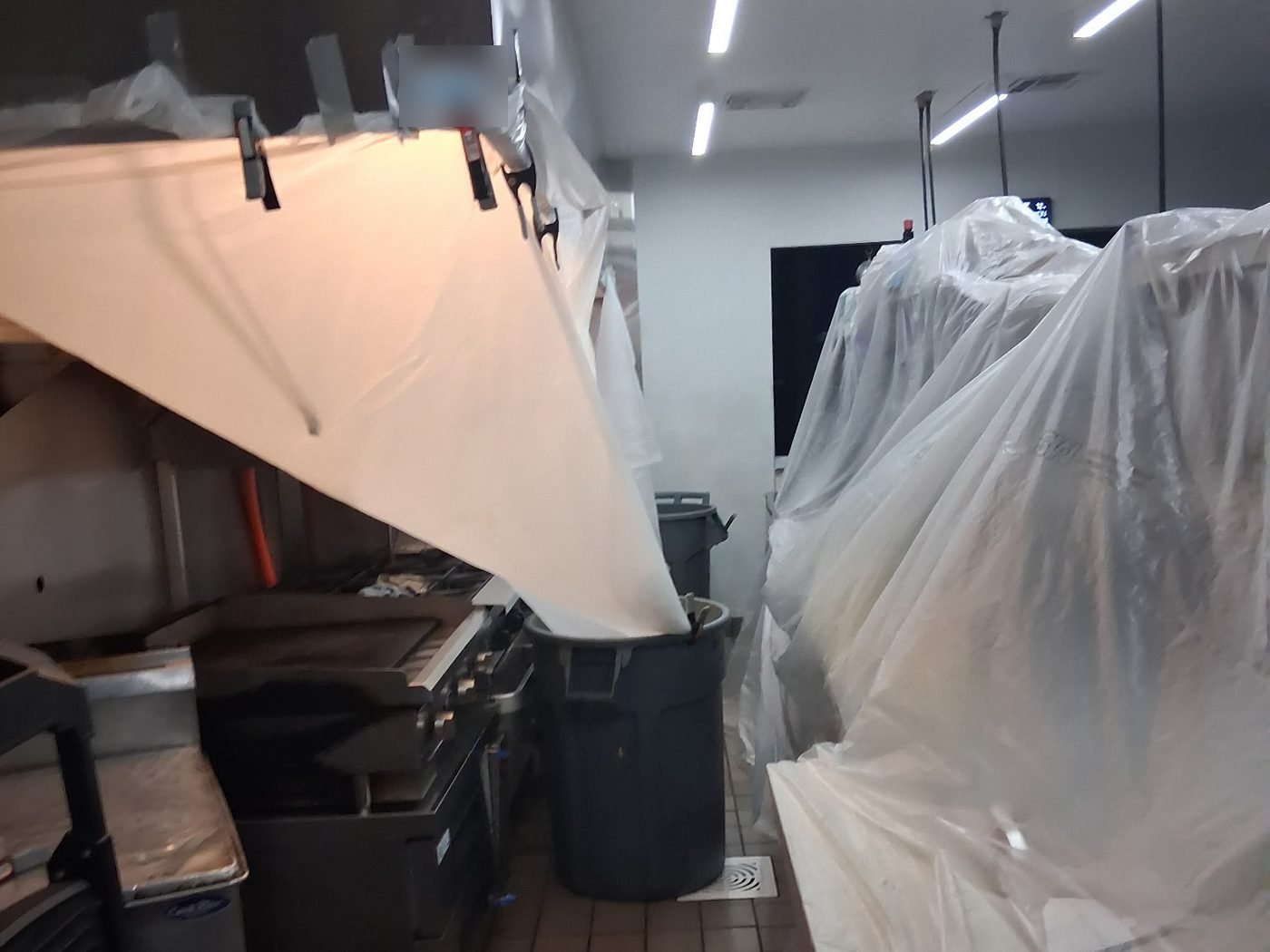 Cook line wrapped in plastic sheeting with a funnel draining hood cleaning runoff into a collection bin